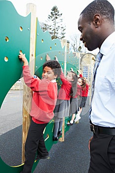 Children On Climbing Wall In School Playground At Breaktime