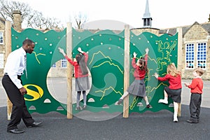 Children On Climbing Wall In School Playground At Breaktime