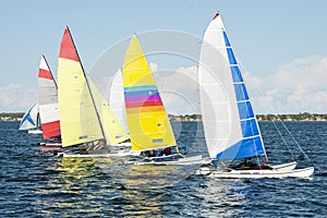 Children close sailing, racing catamarans with brightly coloured sails
