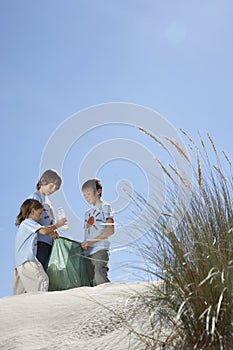 Children Collecting Bottle In Plastic Bag On Beach