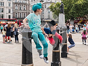 Children in colorful clothes play on iron railings in Trafalgar