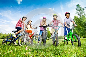 Children in colorful helmets hold their bikes