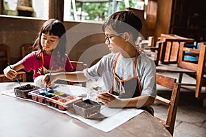 Children coloring clay handicrafts with brushes and paint