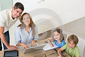 Children coloring while parents using laptop