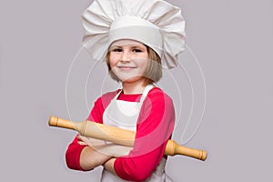 Children cook. Happy little girl in chef uniform holds rolling pin isolated on white background