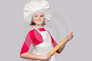 Children cook. Happy little girl in chef uniform holds rolling pin isolated on white background