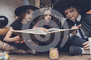 Children in the costumes of monsters with interest consider the spellbook
