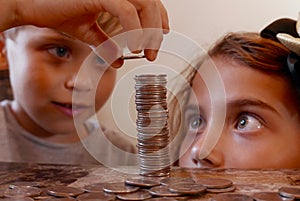 Children counting and stacking coins on a table