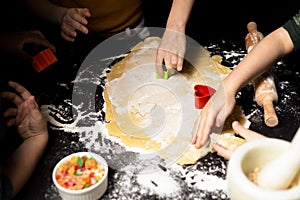 Children cut cookies from dough. Joint friendly cooking. Shortcrust pastry on a dark table and various forms for cutting