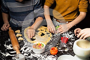 Children cut cookies from dough. Joint friendly cooking. Shortcrust pastry on a dark table and various forms for cutting