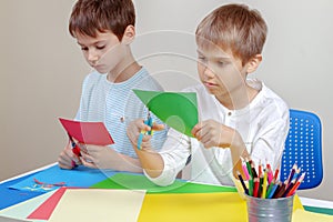 Children cutting colored paper with scissors at the table