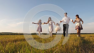Children, dad and mom play in meadow in the sunshine. mother, father and little daughter with sisters walking in field
