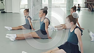 Children in a dance lesson. little girls sit on the floor and repeat the movements behind the teacher