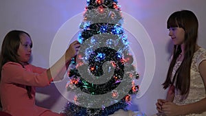 Children decorates the Christmas tree with Christmas balls. small kids plays by Christmas tree in children`s room