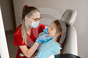 Children dentist examines child girl mouth and teeth and treats toothaches. Happy child patient of dentistry