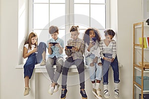 Children of different nationalities play online games or read social networks on mobile phones.