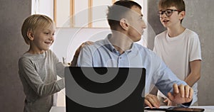 Children distract dad from work. Young male freelancer trying to work at home with two children.