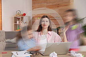 Children disturbing overwhelmed woman in living room. Working from home during quarantine