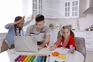 Children disturbing stressed man in kitchen. Working from home during quarantine