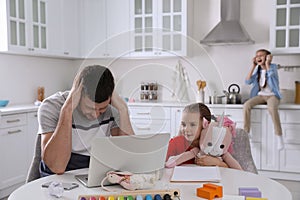 Children disturbing stressed man in kitchen. Working from home during quarantine