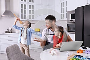 Children disturbing stressed man in kitchen. Working from home during quarantine