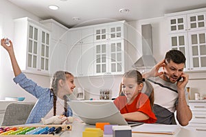 Children disturbing stressed man in kitchen. Working from home during quarantine