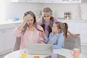 Children disturbing stressed woman in kitchen. Working from home during quarantine