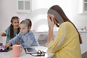 Children disturbing stressed woman in kitchen. Working from home during quarantine