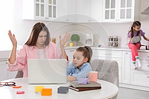 Children disturbing stressed woman in kitchen. Working from home during quarantine