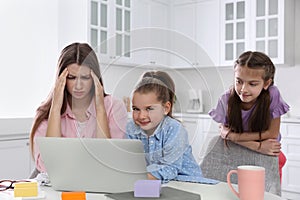 Children disturbing stressed woman in kitchen. Working from home during quarantine