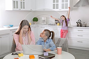 Children disturbing stressed woman in kitchen. Working from home during quarantine