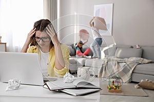 Children disturbing stressed woman in living room. Working from home during quarantine