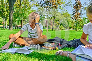 Children do homework in the park, a boy and a girl are preparing for school
