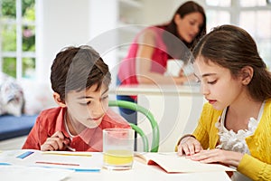 Children Doing Homework As Mother uses Laptop