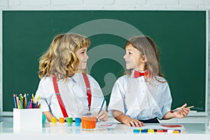 Children doing school lesson at class. Funny school girl an boy pupil drawing a picture. Cute little preschoolers