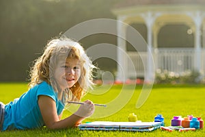 Children draw paint pictures outside, childrens creativity. Child boy drawing in summer park, painting art. Little