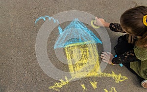 Children draw the Ukrainian flag house on the pavement. Selective focus.