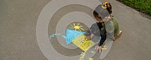 Children draw the Ukrainian flag house on the pavement. Selective focus.