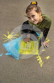 Children draw the Ukrainian flag house on the pavement. Selective focus.