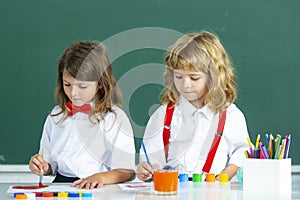 Children in drawing school lesson at class. Funny school girl an boy pupil drawing a picture. Cute little preschoolers