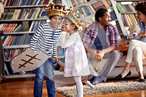 Children dressed as knights whisper and murmur while playing with their parents at home. Family, home, playtime