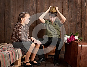 Children are dressed in retro military uniforms sending a soldier to the army, dark wood background, retro style