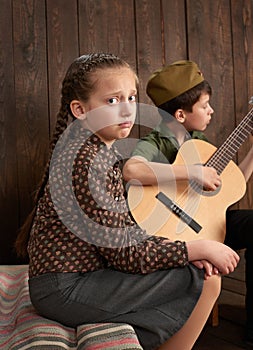 Children are dressed in retro military uniforms sending a soldier to the army, dark wood background, retro style