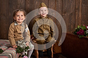 Children are dressed in retro military uniforms sending a soldier to the army, dark wood background, retro style