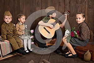Children are dressed in retro military uniforms sitting and playing guitar, sending a soldier to the army, dark wood background, r
