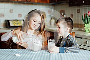 Children drink milk in the kitchen at the morning.