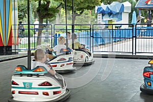 Children drive electric cars in the amusement park. Happy childhood. Theme park. Driving bumper car