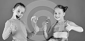 Children eat big colorful sweet caramels. Sisters with lollipops