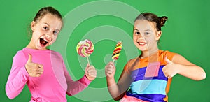 Children eat big colorful sweet caramels. Sisters with lollipops