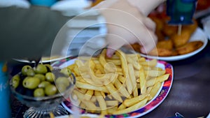 Children eat French fries at party. Children's hands take potatoes from place in close-up. Fast food, junk food
